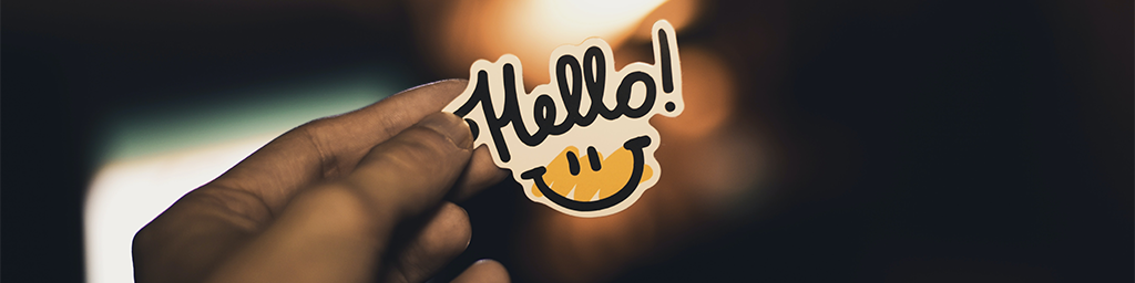 Person holding some paper with the word hello and a smiling face below